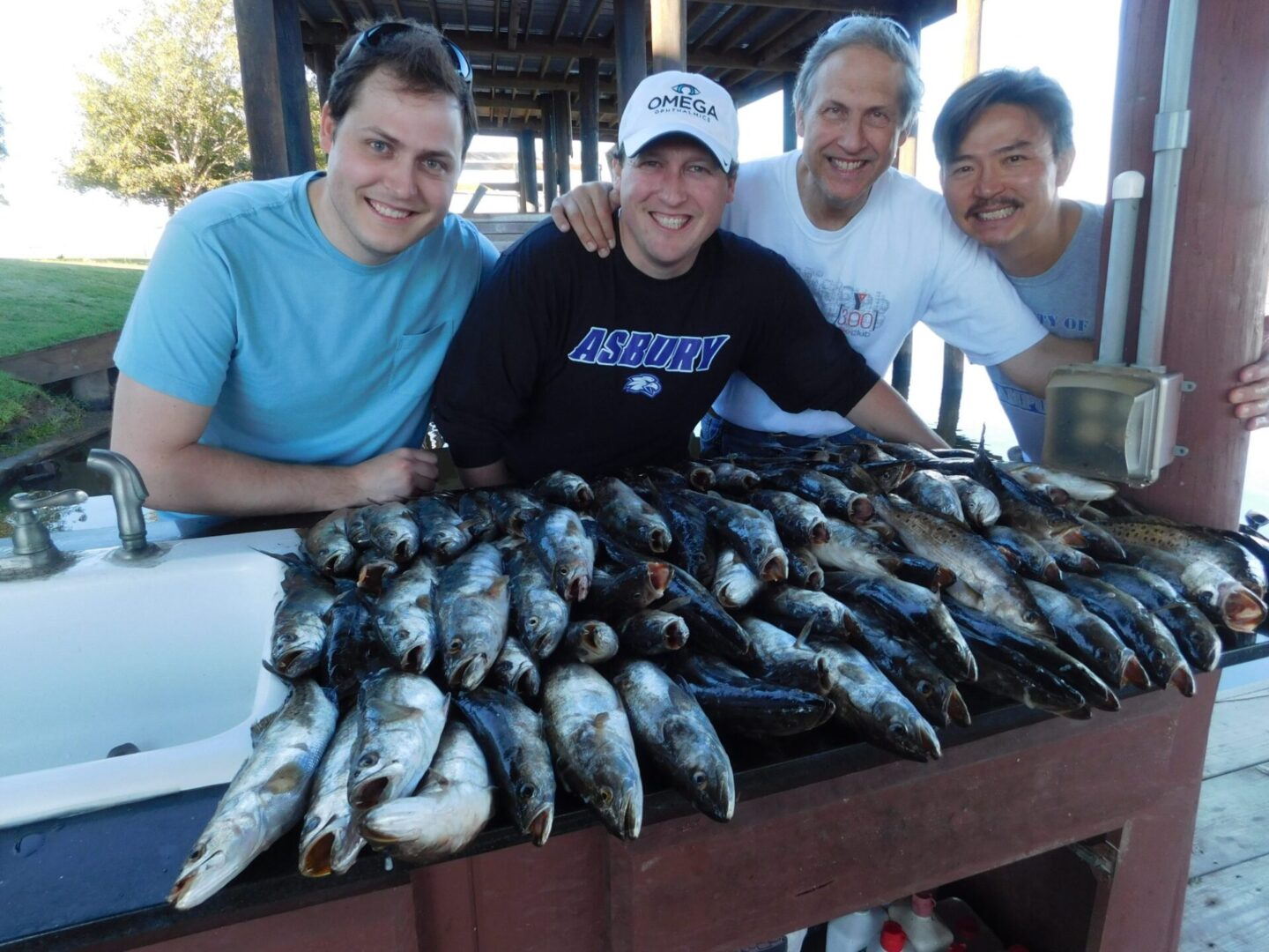 A group of men standing around a table full of fish.