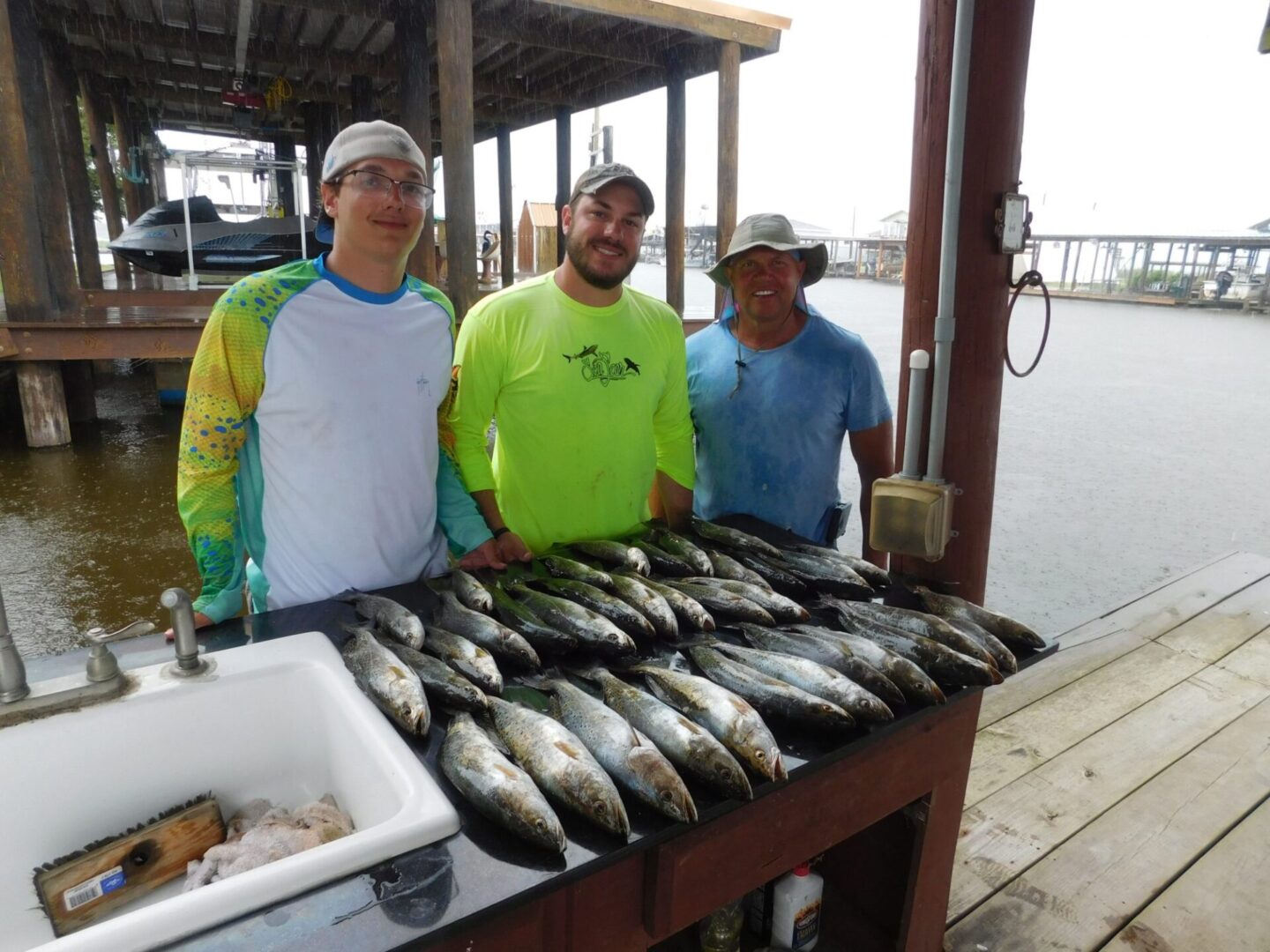 Three men standing next to a table with fish.